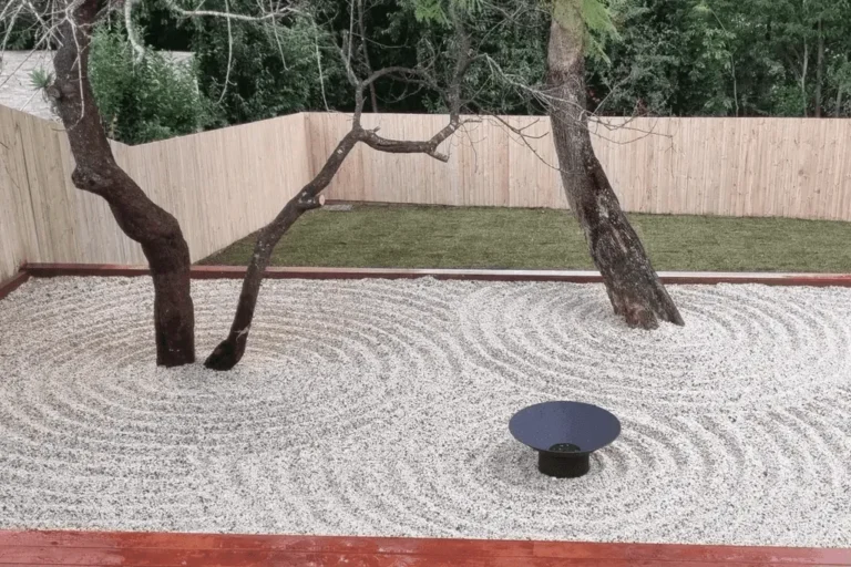 Arianya’s minimalist Zen garden at Beaumont Rd, Killara NSW 2071, Australia, featuring raked gravel patterns, mature trees, and a sleek fire bowl for serene outdoor living.