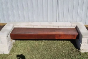 Sydney garden featuring a custom wooden bench by Arianiya Landscapes, with a brick wall and grassy lawn.