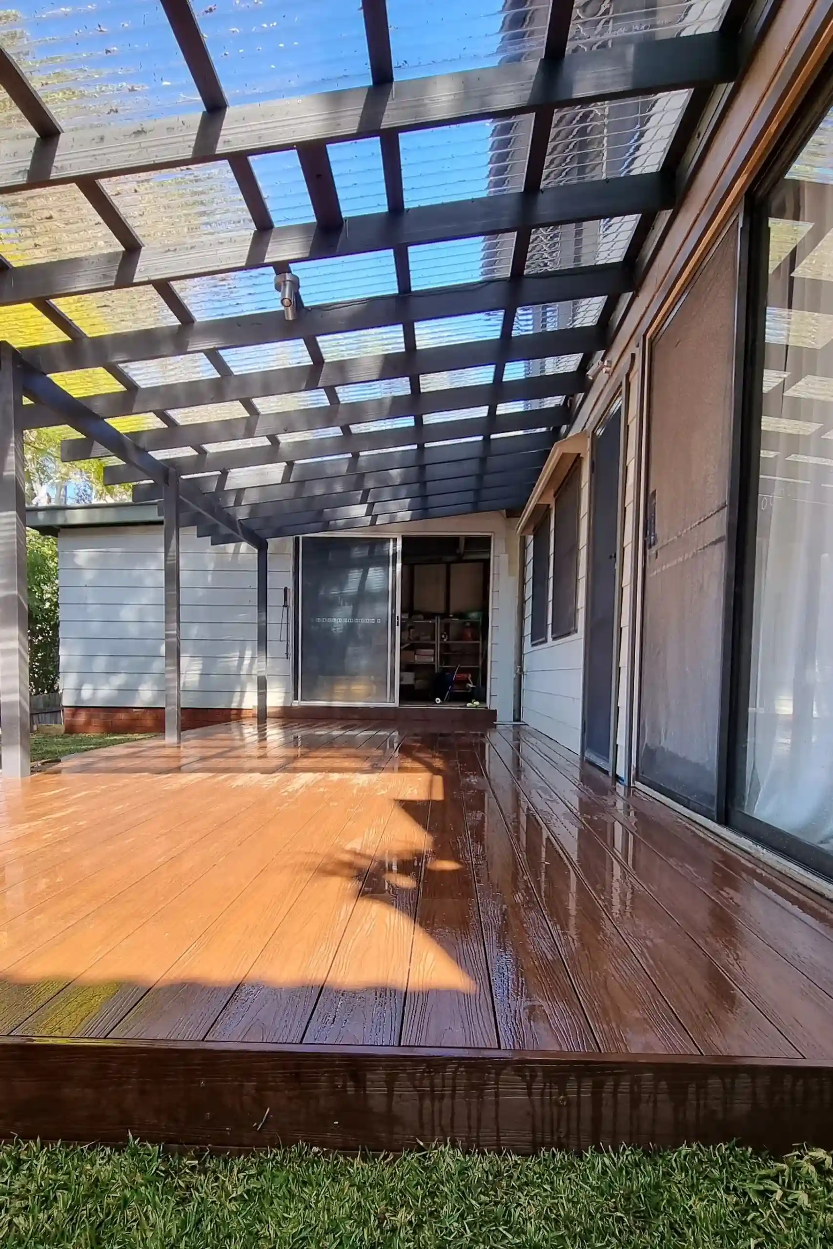 A stylish outdoor aluminium pergola with a transparent roof, constructed by Ariyania Landscapes.