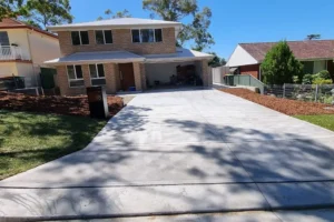 A newly laid, smooth concrete driveway stretches towards a modern brick house in Sydney.