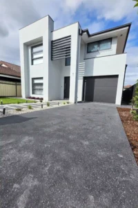 Refinish concrete driveway by Ariyania Landscapes in Sydney, leading to a modern home.