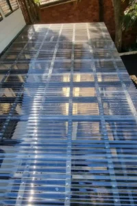 Close-up view of a recently installed pergola roof with clear corrugated polycarbonate sheets, showcasing the quality of Ariyania Landscapes' pergola construction service.