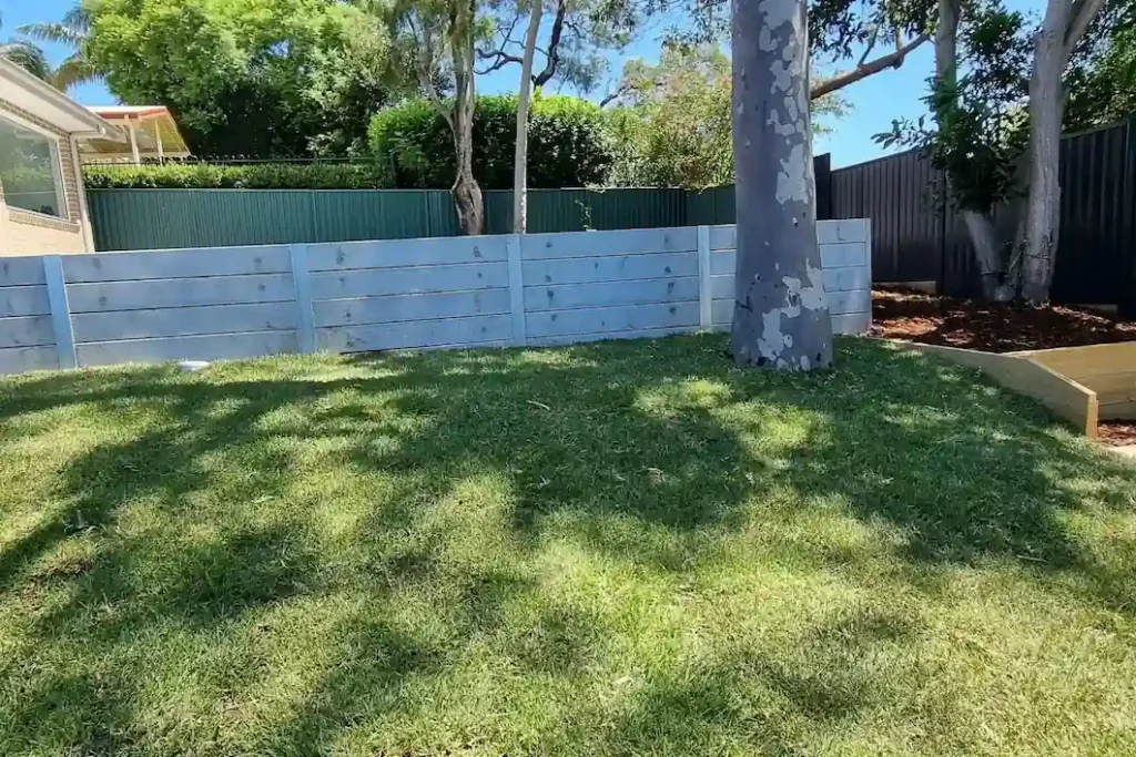 Expert pool landscaping by Arianya in Sydney, featuring a lush lawn, sturdy retaining wall, and mature trees, creating a serene backyard oasis for Sydney homes.