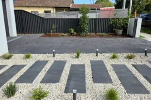 simple paving design for a driveway and garden path, featuring dark pavers set in white gravel and complemented